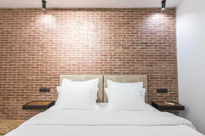 a bed with white pillows in front of a brick wall at Athens Oasis in Athens