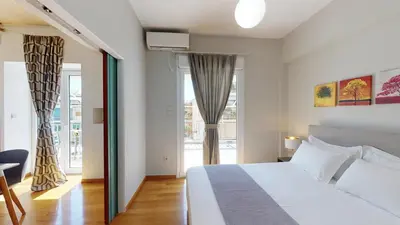 a bedroom with a white bed and a large window at Penthouse of light @ Koukaki in Athens