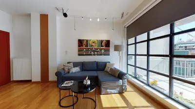 a living room with a blue couch and a large window at Penthouse of light @ Koukaki in Athens