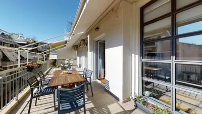 a balcony with a wooden table and chairs on a building at Penthouse of light @ Koukaki in Athens