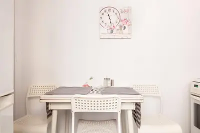 a white table with chairs and a clock on the wall at Top GroundFloor in Mets in Athens