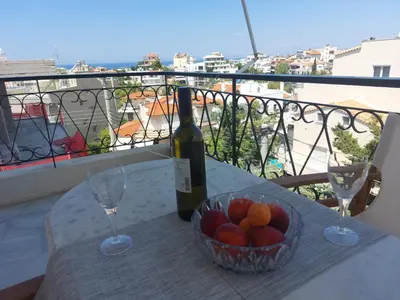 a bottle of wine and a bowl of fruit on a table at Sea view,big and comfortable appartment in Voula in Athens