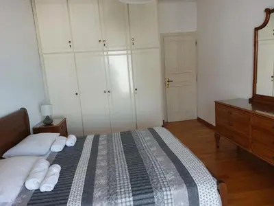 a bedroom with a bed with white pillows and a dresser at Sea view,big and comfortable appartment in Voula in Athens