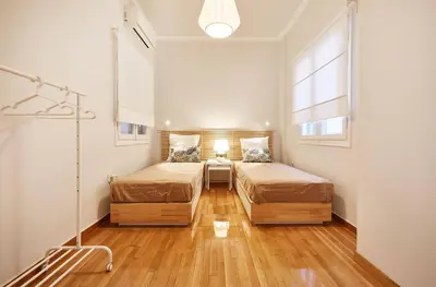 a bedroom with two beds and a table and a window at Chloe Boutique Apartments Metropolis in Athens