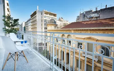 a balcony with a white chair and some buildings at Chloe Boutique Apartments Metropolis in Athens