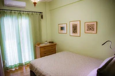 a bedroom with a bed and a dresser and a window at Sophie's Penthouse in Athens in Athens
