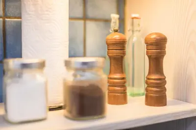 a shelf with glass bottles and a wooden chessernel at Amazing Apartment Pallini - Near Airport & Metro in Pallíni