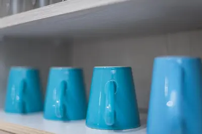 a row of blue cups sitting on a shelf at Amazing Apartment Pallini - Near Airport & Metro in Pallíni
