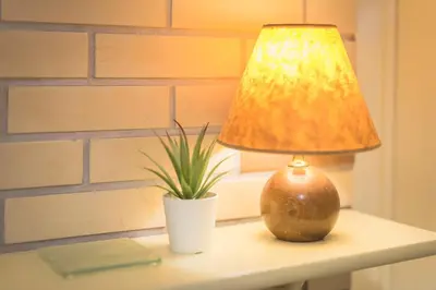 a lamp sitting on a table next to a potted plant at Amazing Apartment Pallini - Near Airport & Metro in Pallíni