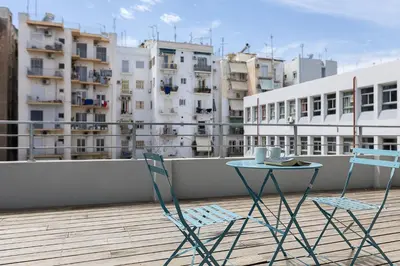 two chairs and a table on a balcony with buildings at The Omnia Collection Pagrati in Athens