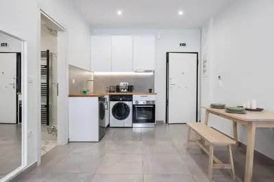 a kitchen with white cabinets and a table and a stove at The Omnia Collection Pagrati in Athens