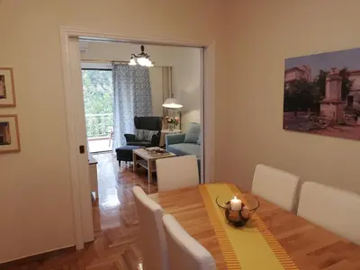 a dining room and living room with a table and chairs at Parthenon View Apt in Athens