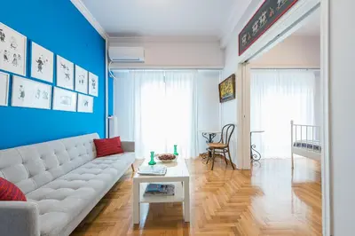 a living room with a white couch and a blue wall at Athens Centre Flat 2 min. from Evangelismos Metro in Athens