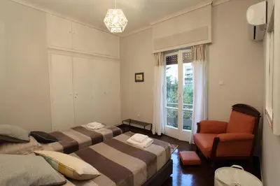 a room with two beds and a chair and a window at Stylish Flat at Edem Beach by Athenian Homes in Athens