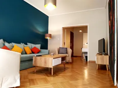 a living room with a blue couch with colorful pillows at 24 times Athens in Athens