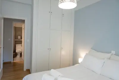 a white bedroom with a white bed and a bathroom at 24 times Athens in Athens
