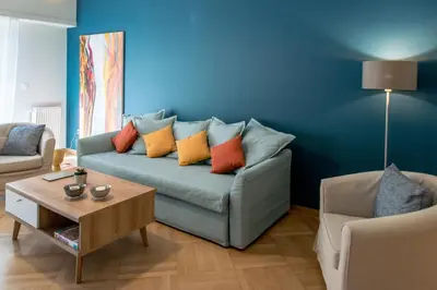 a living room with a blue couch with colorful pillows at 24 times Athens in Athens
