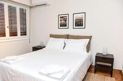 a bedroom with a large white bed with two tables at Central apartment at Echarxia 2 beds for 5 pers by MPS in Athens