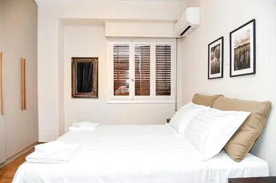 a white bedroom with a bed and a window at Central apartment at Echarxia 2 beds for 5 pers by MPS in Athens