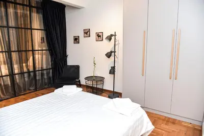 a bedroom with a white bed and a chair at Central apartment at Echarxia 2 beds for 5 pers by MPS in Athens