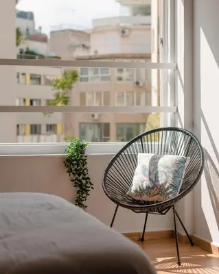 a wicker chair sitting on a balcony with a window at Môss Suite - Monastiraki Square View in Athens