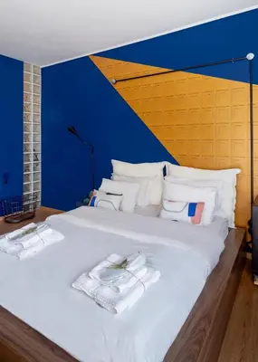 a large white bed with a blue and yellow wall at Môss Suite - Monastiraki Square View in Athens
