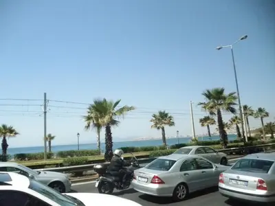 a man on a motorcycle in a parking lot with cars at Dreaming Stay in Athens