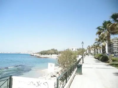 a sidewalk next to the beach with palm trees at Dreaming Stay in Athens
