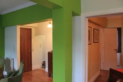 a living room with green walls and a hallway at Acropolis Apartment in Athens