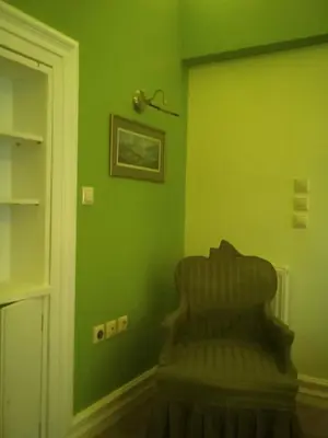 a green wall with a chair in a room at Acropolis Apartment in Athens