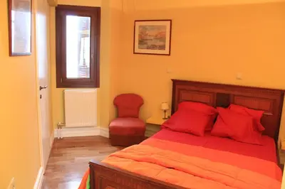 a bedroom with a bed with red pillows and a chair at Acropolis Apartment in Athens