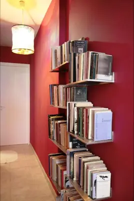 a book shelf filled with books against a red wall at Mets Area, Hip, Tasteful & Ultra Convenient Studio for 2 in Athens