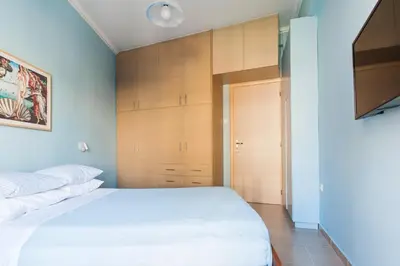 a bedroom with a white bed and wooden cabinets at Athens Casa Bonita in Athens