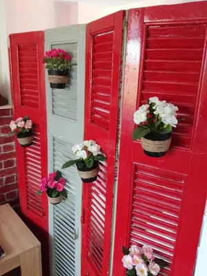 a red shutter door with potted flowers on it at LITTLE HOUSE ON THE ROOFTOP in Athens