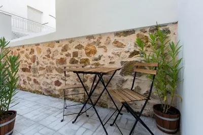 a table and two chairs in front of a stone wall at Dinostratus House - Boutique Studios in Athens