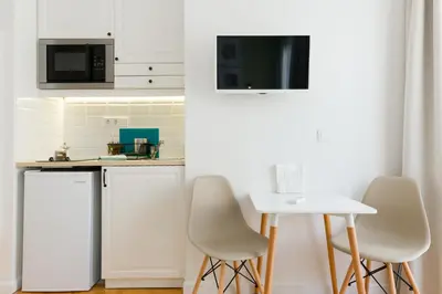 a kitchen with white appliances and a white table and chairs at Dinostratus House - Boutique Studios in Athens