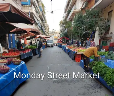 a market with a man standing in a street with fruits and vegetables at Dinostratus House - Boutique Studios in Athens