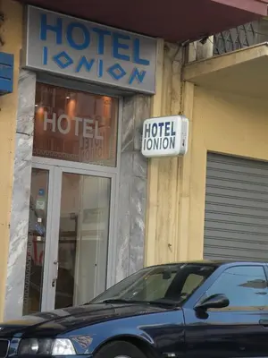 a hotel sign and a car parked in front of a store at Hotel Ionion in Piraeus