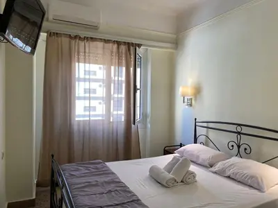 a bedroom with a bed with white pillows and a window at Hotel Ionion in Piraeus