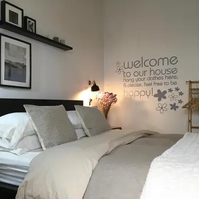 a bedroom with a bed with a welcome to our house sign on the wall at Evelina’s apartment in Athens