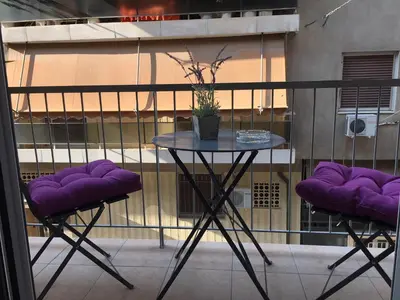 a table and two purple chairs on a balcony at Bring only your toothbrush! in Athens