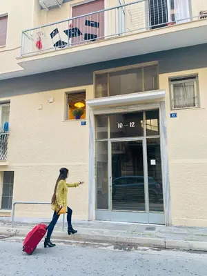 a woman walking down the street with her luggage at Bring only your toothbrush! in Athens