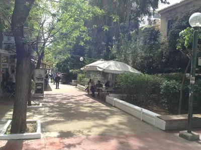 a sidewalk with people sitting under an umbrella at Kleopatra Apartment in Acropolis in Athens