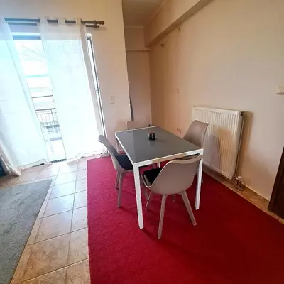 a dining room with a table and chairs on a red rug at Horizon apartment Athens near to Acropolis, sea & subway in Athens