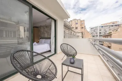 a balcony with two chairs and a bed on it at Athens Lights in Athens