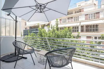a patio with two chairs and an umbrella on a balcony at Athens Lights in Athens