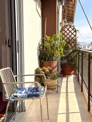 a balcony with chairs and potted plants on it at Friends & Family in Athens