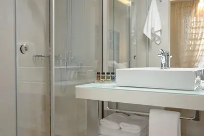 a bathroom with a sink and a shower with towels at Athens Platinum Rooms and Suites in Athens