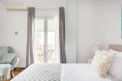 a bedroom with a bed and a chair and a window at Romantic Love-Nest Studio Near Acropolis & Metro in Athens