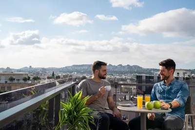 two men sitting at a table on a balcony at Chroma Fashion Rooms & Apartments in Athens